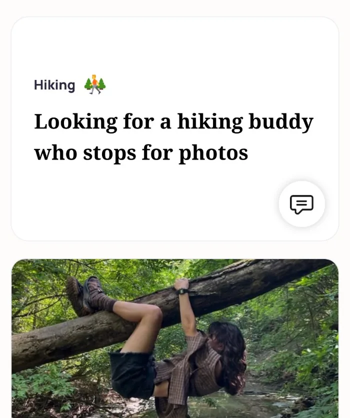 An Alyke profile card for Hiking that reads: Looking for a hiking buddy who stops for photos, above a photo of the member hanging off a fallen tree over a stream
