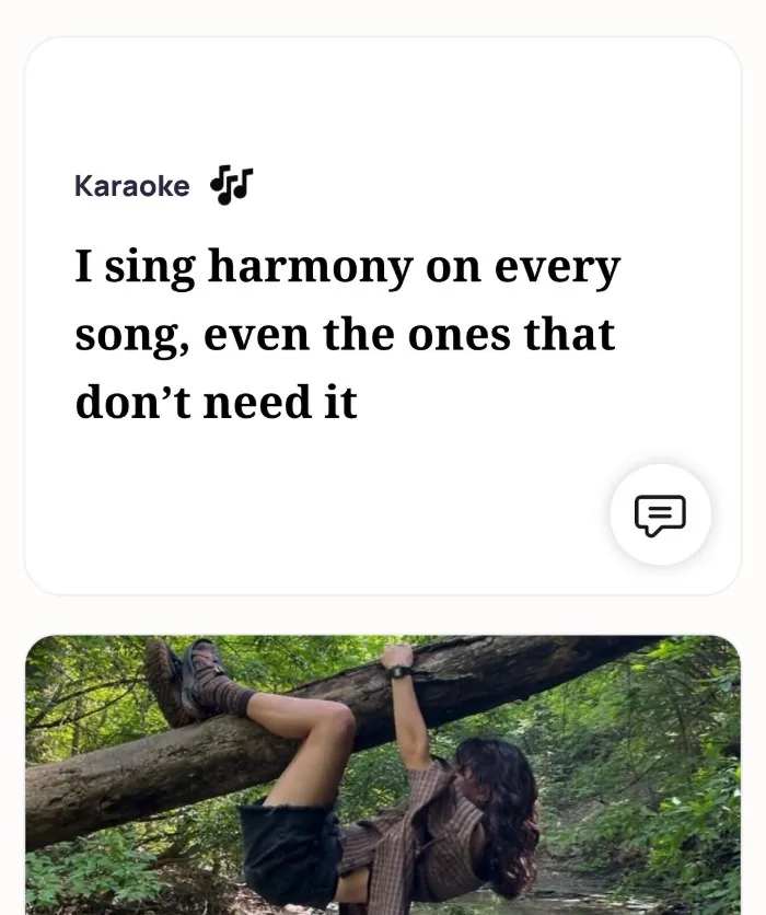 An Alyke profile card for Karaoke that reads: I sing harmony on every song, even the ones that don't need it, above a photo of the member hanging from a fallen tree in a forest