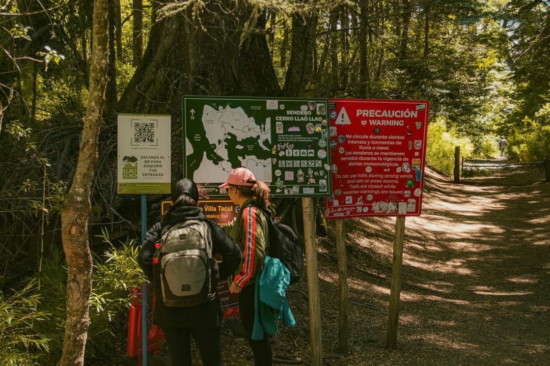 A group of hikers at a trail sign while their leader points at the map