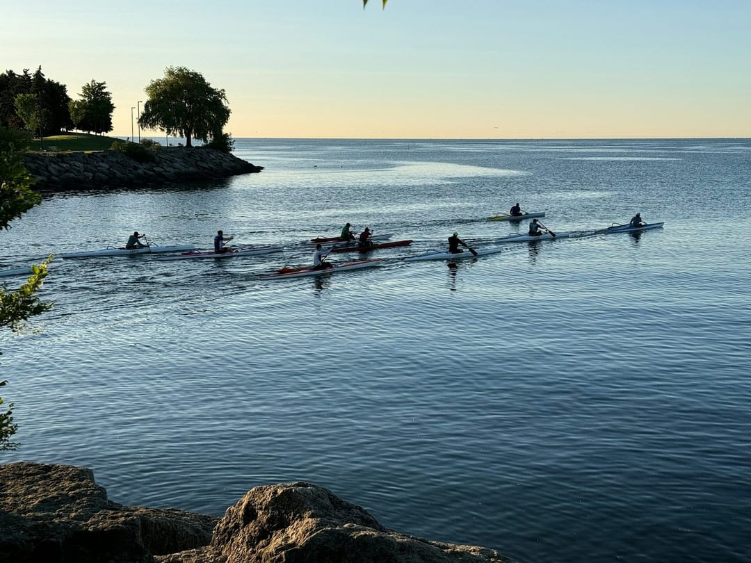 A group launching kayaks on a lake at sunrise