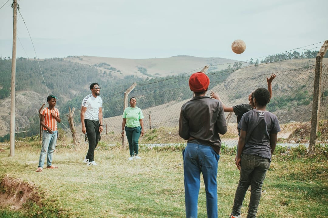 A kickball team laughing on a park field at dusk