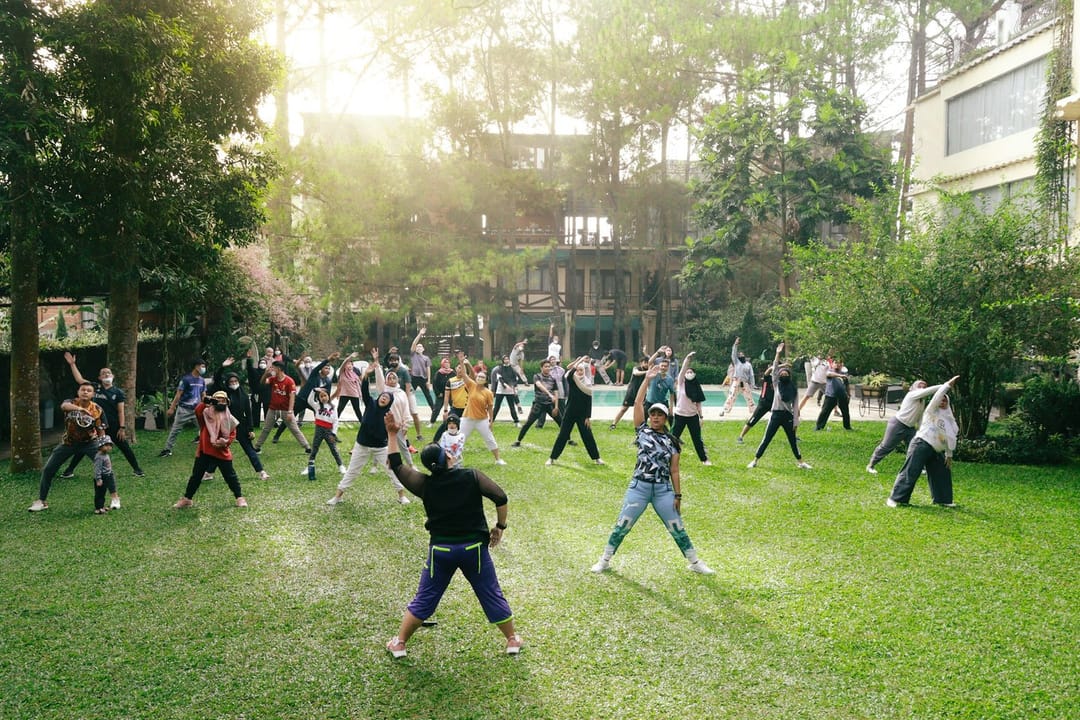 An outdoor fitness class on a waterfront lawn at dusk