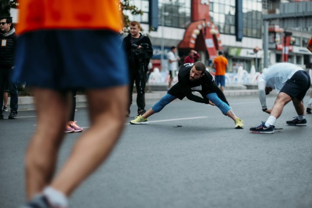 Run club members stretching and chatting outside a coffee shop at dusk