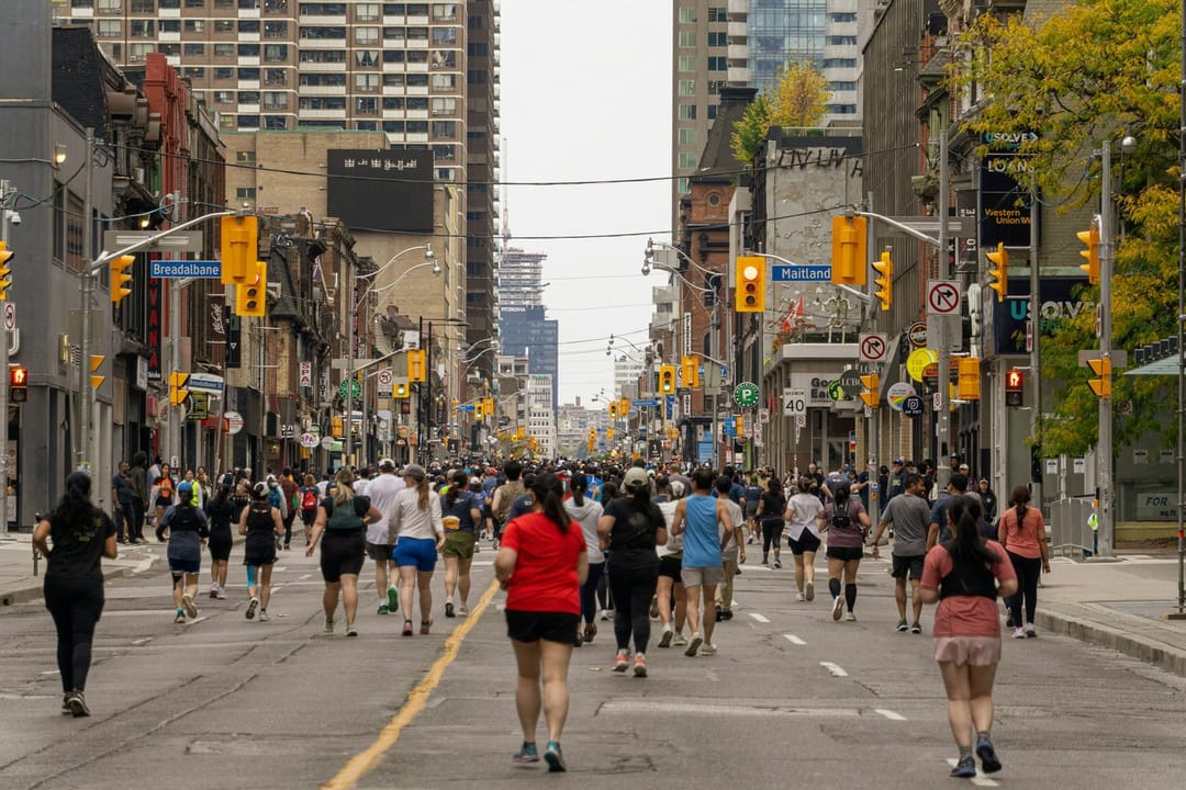 Runners talking at the back of a group run on a brick street at dusk