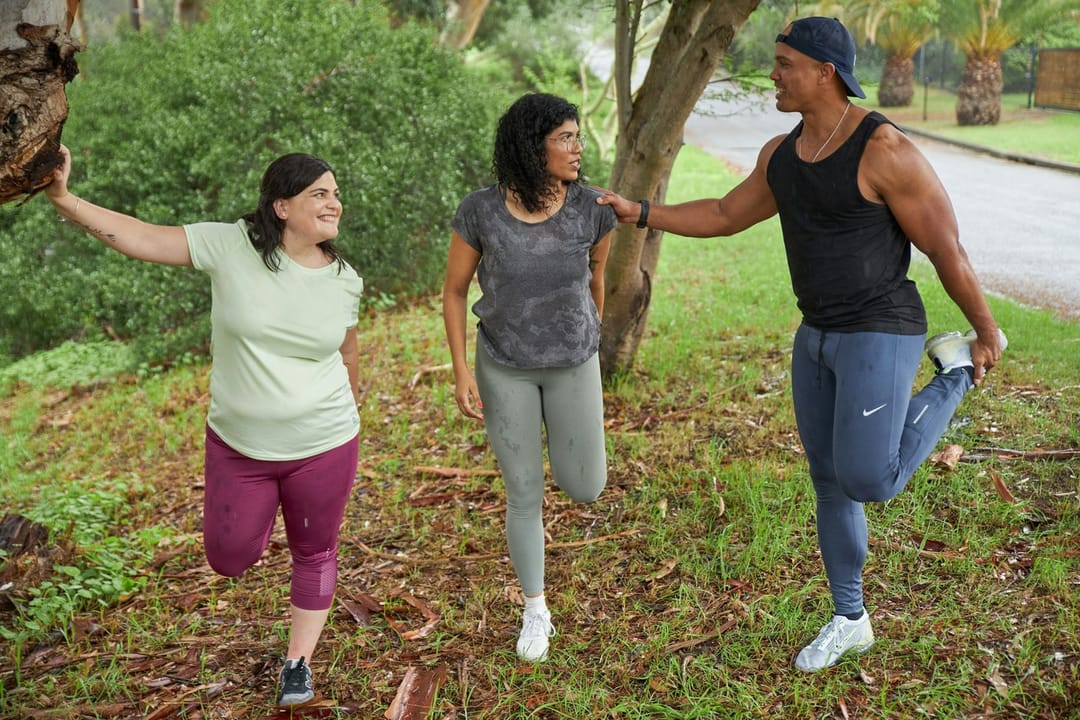 Runners talking while they stretch beside a park track