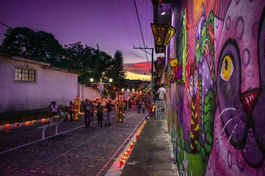 Runners and walkers on a mural-lined trail heading toward a brewery patio at dusk
