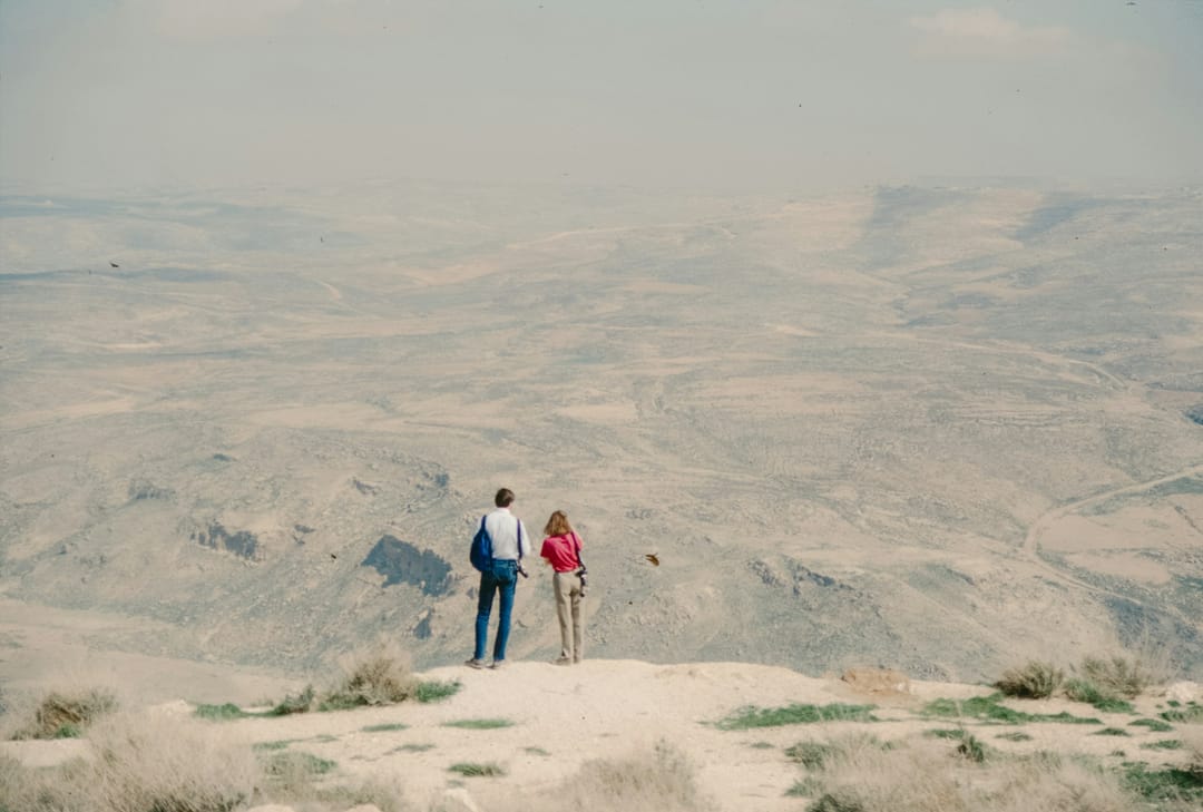 Two friends on a desert summit at sunrise with saguaros below