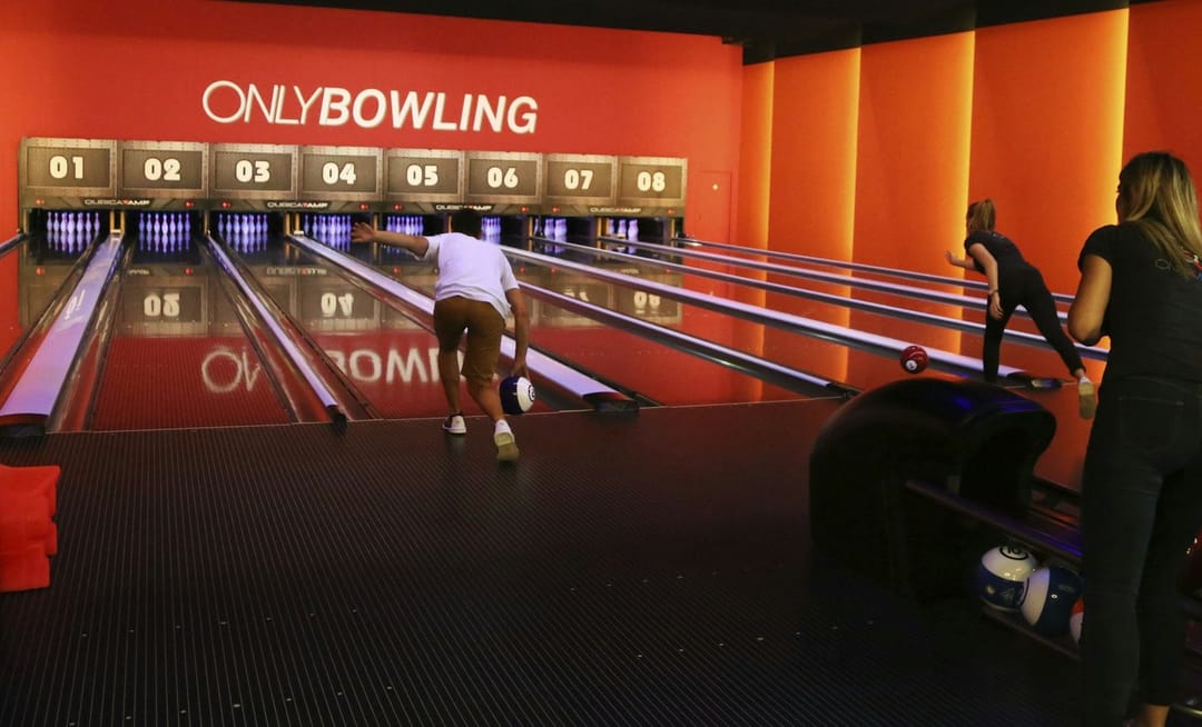 Two friends laughing at a bowling alley after a strike
