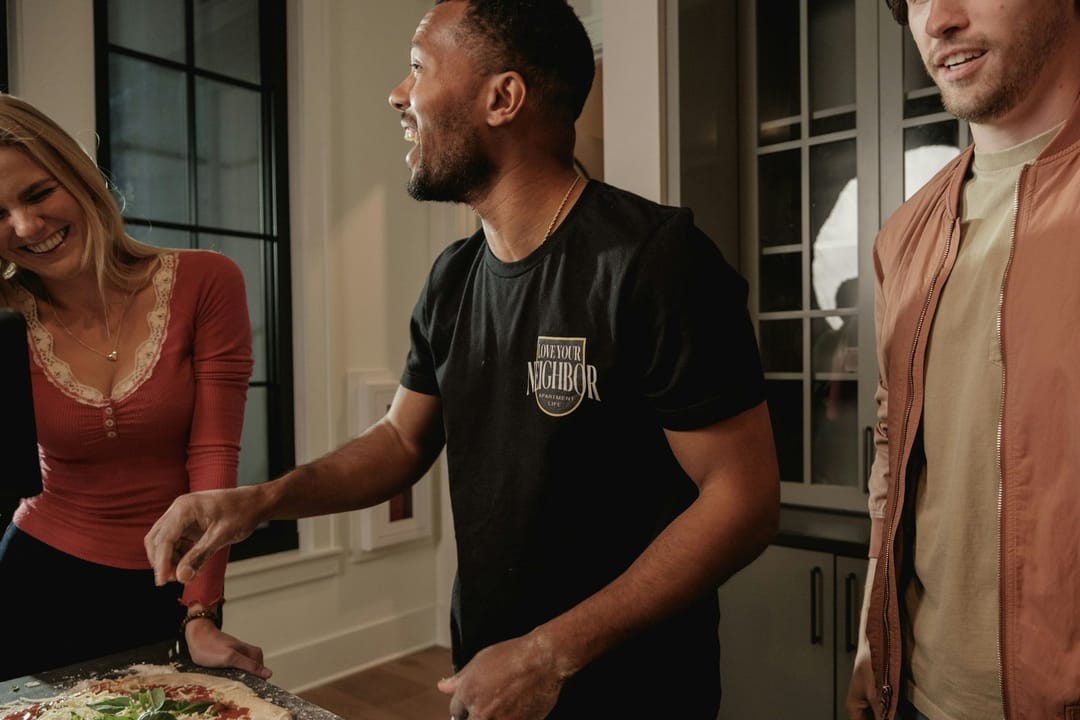 Two friends laughing while they cook together in a small apartment kitchen