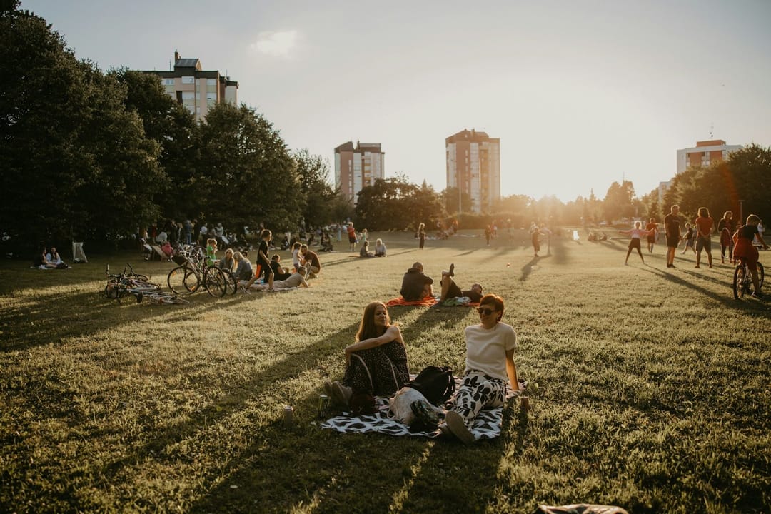 Two friends on a picnic blanket before an outdoor movie in a park