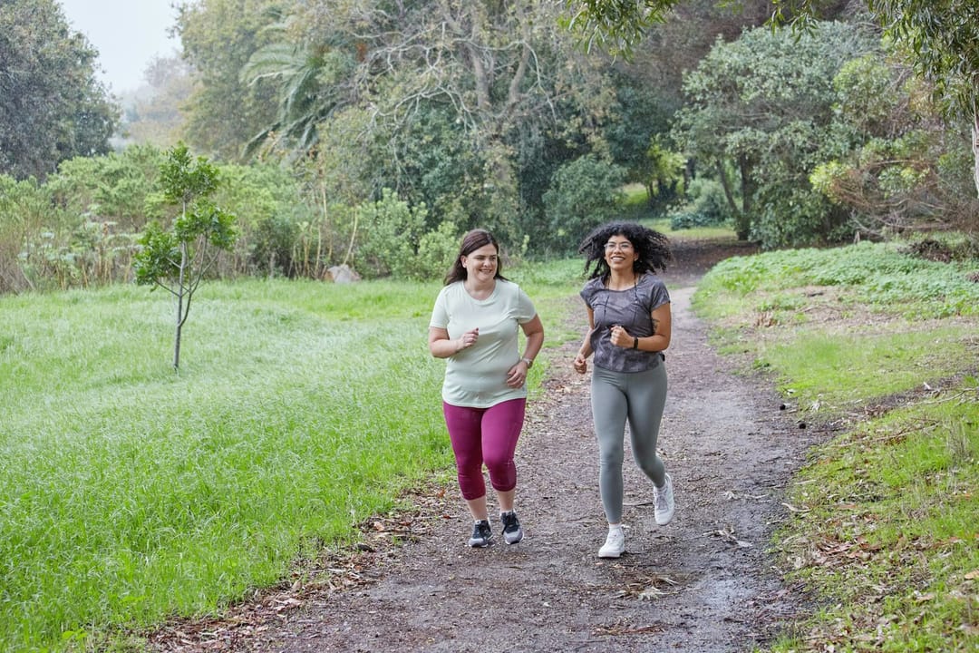 Two friends talking as they run side by side along a river at dusk