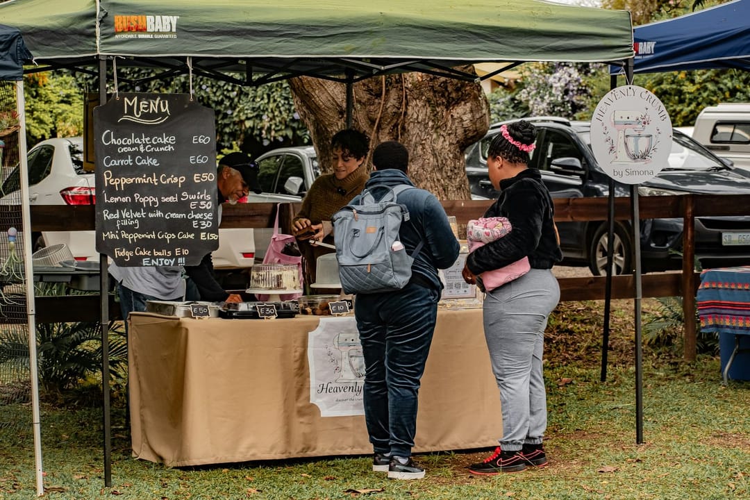 Two friends tasting peaches at a farmers market stall