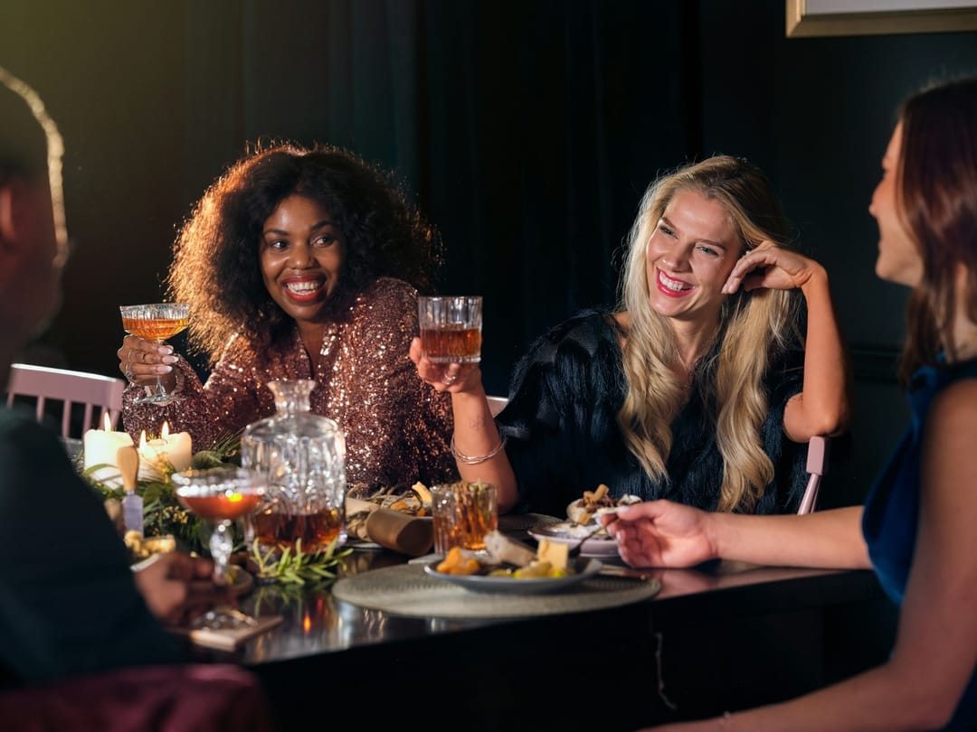 Two friends whispering answers at a bar trivia night