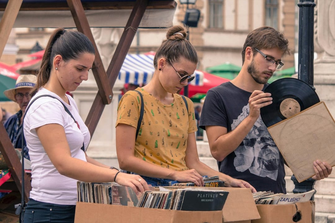 Two people comparing records in a store aisle