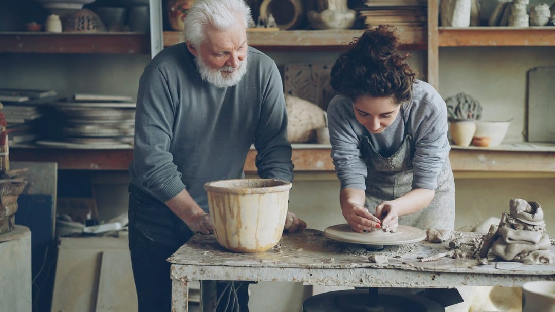 Two people laughing over a lopsided bowl at a pottery class