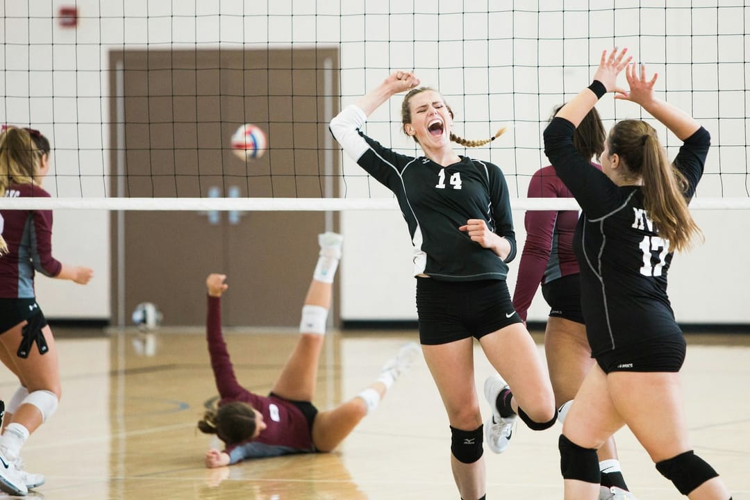 Two rec-league volleyball teammates high-fiving at the net