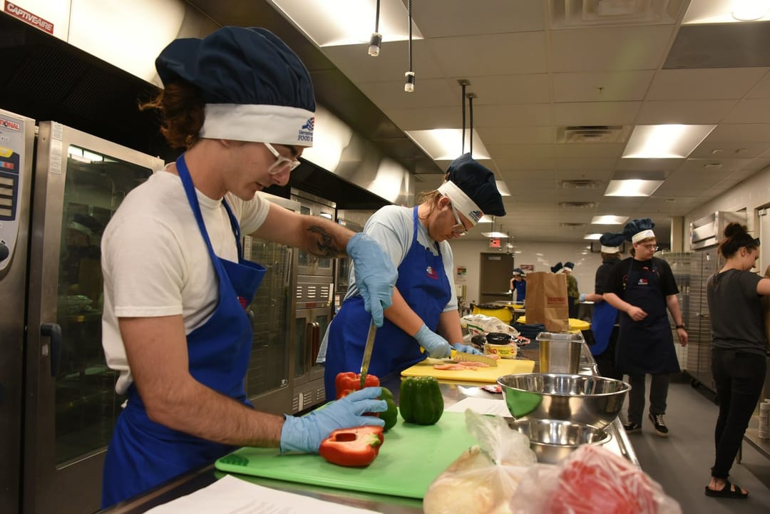 Two volunteers laughing at a kitchen prep table