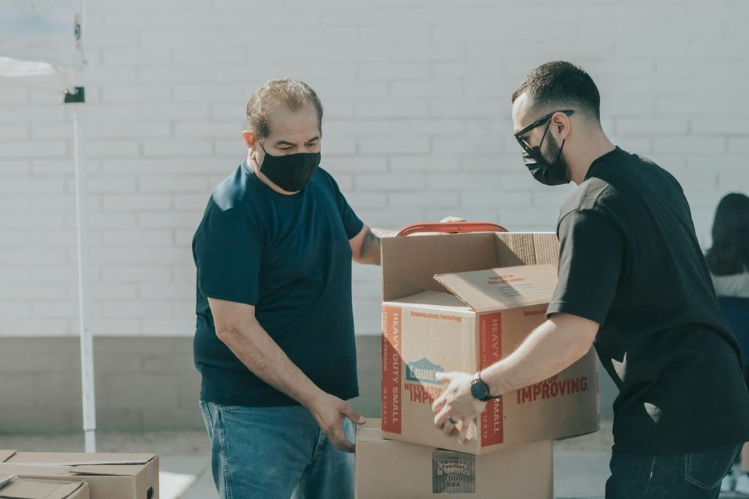 Two volunteers laughing while packing boxes at a food bank