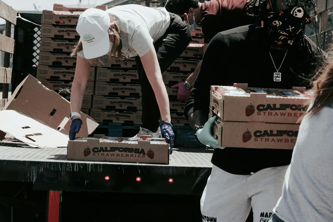 Two volunteers talking while packing food boxes at a food bank