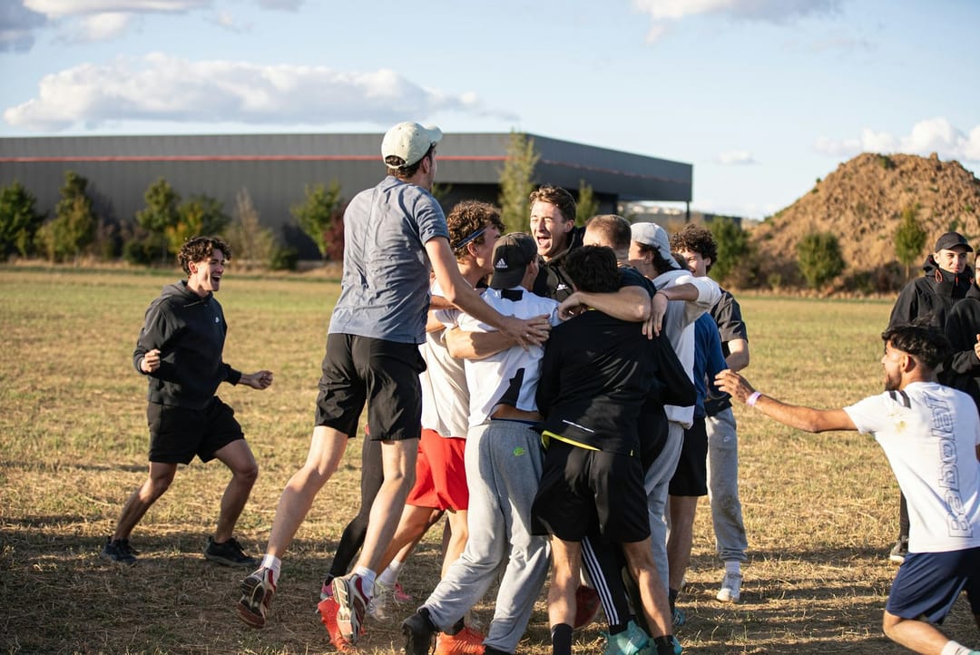 An ultimate frisbee team huddled on a floodlit field