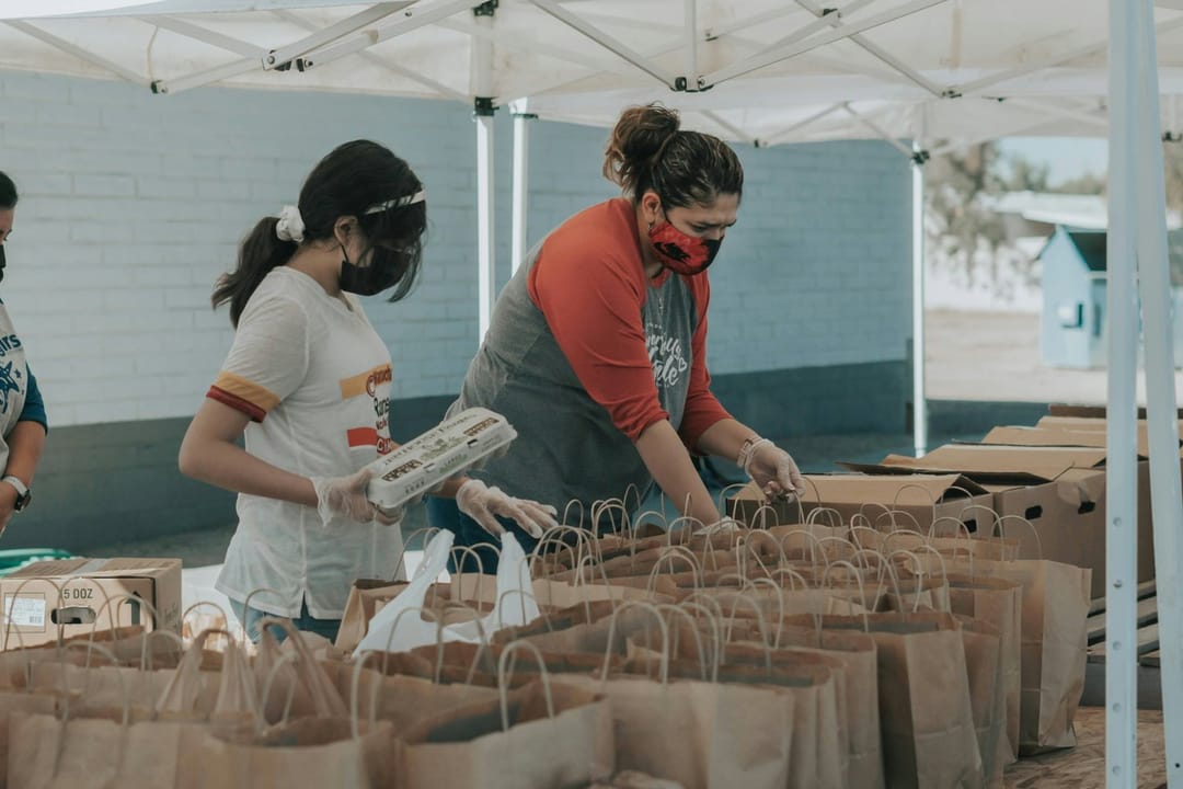 Volunteers laughing while packing boxes at a food bank