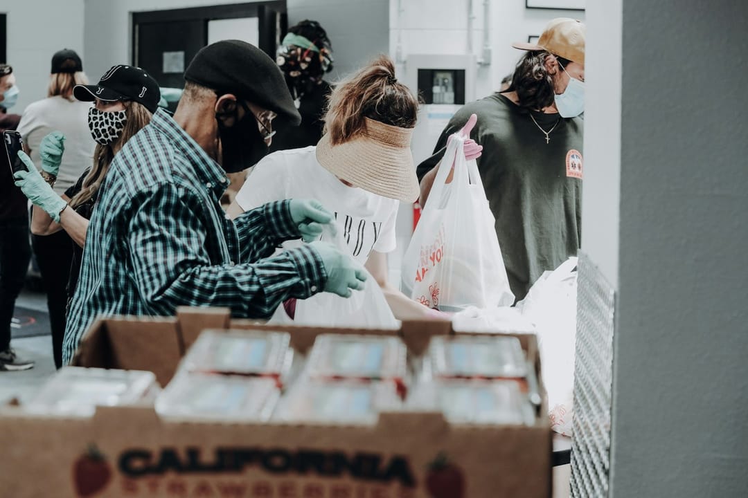 Volunteers laughing while sorting produce at a food bank