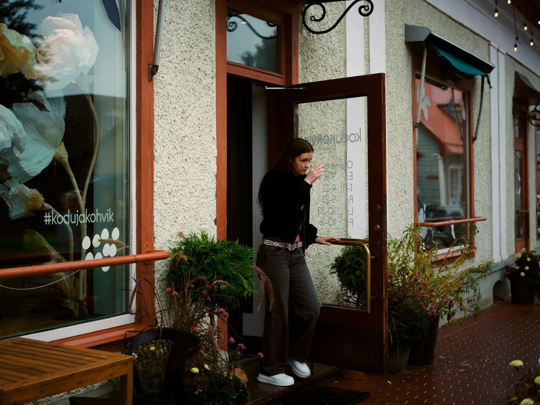 A woman texting a friend by her front door before heading out