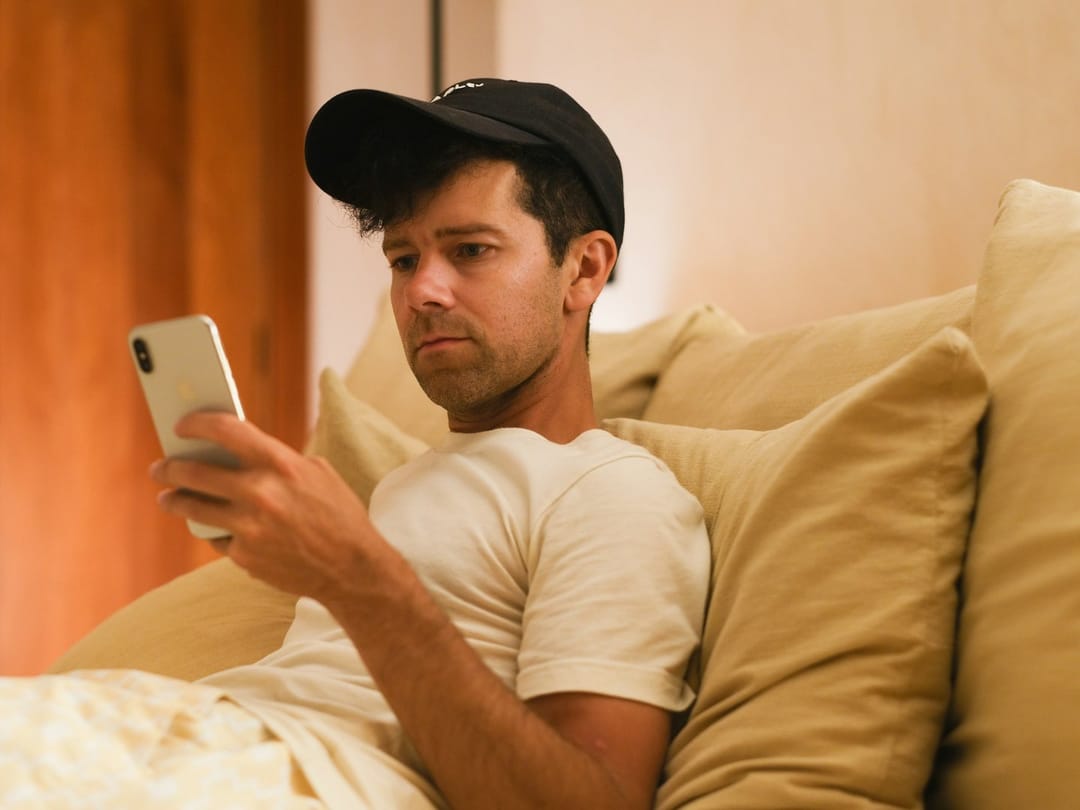 A young person on their bed in the evening, rewriting a message on their phone