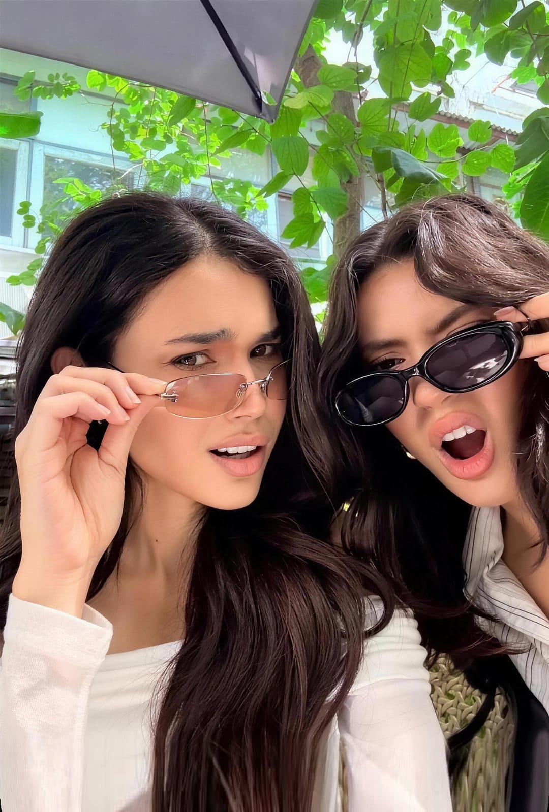 Two friends lowering their sunglasses at the camera at the same moment